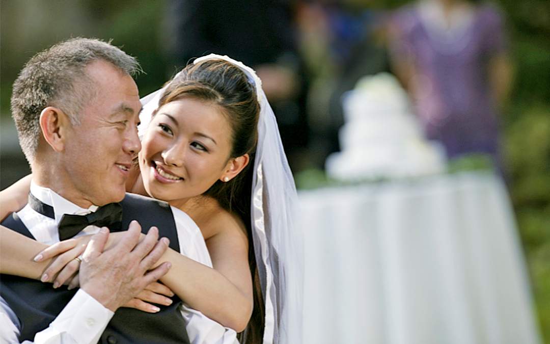 Bride hugging and smiling at her father during wedding reception.