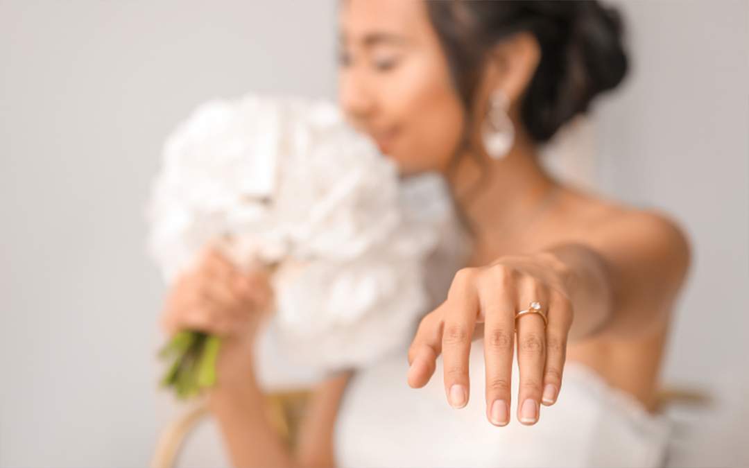 Bride holding out her left hand to show her diamond engagement ring.