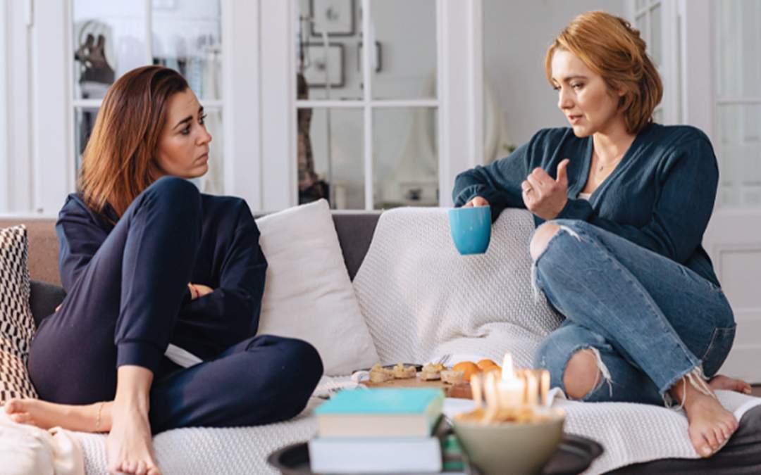 Two women sitting on couch having stressful conversation.